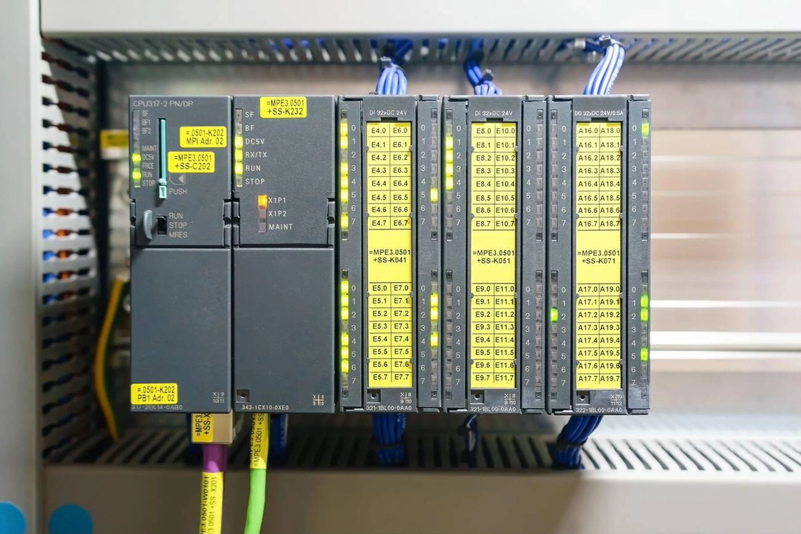 یک ماژول زرد رنگ Safety PLC در کنار یک دکمه توقف اضطراری برای حفاظت از جان کارکنان.